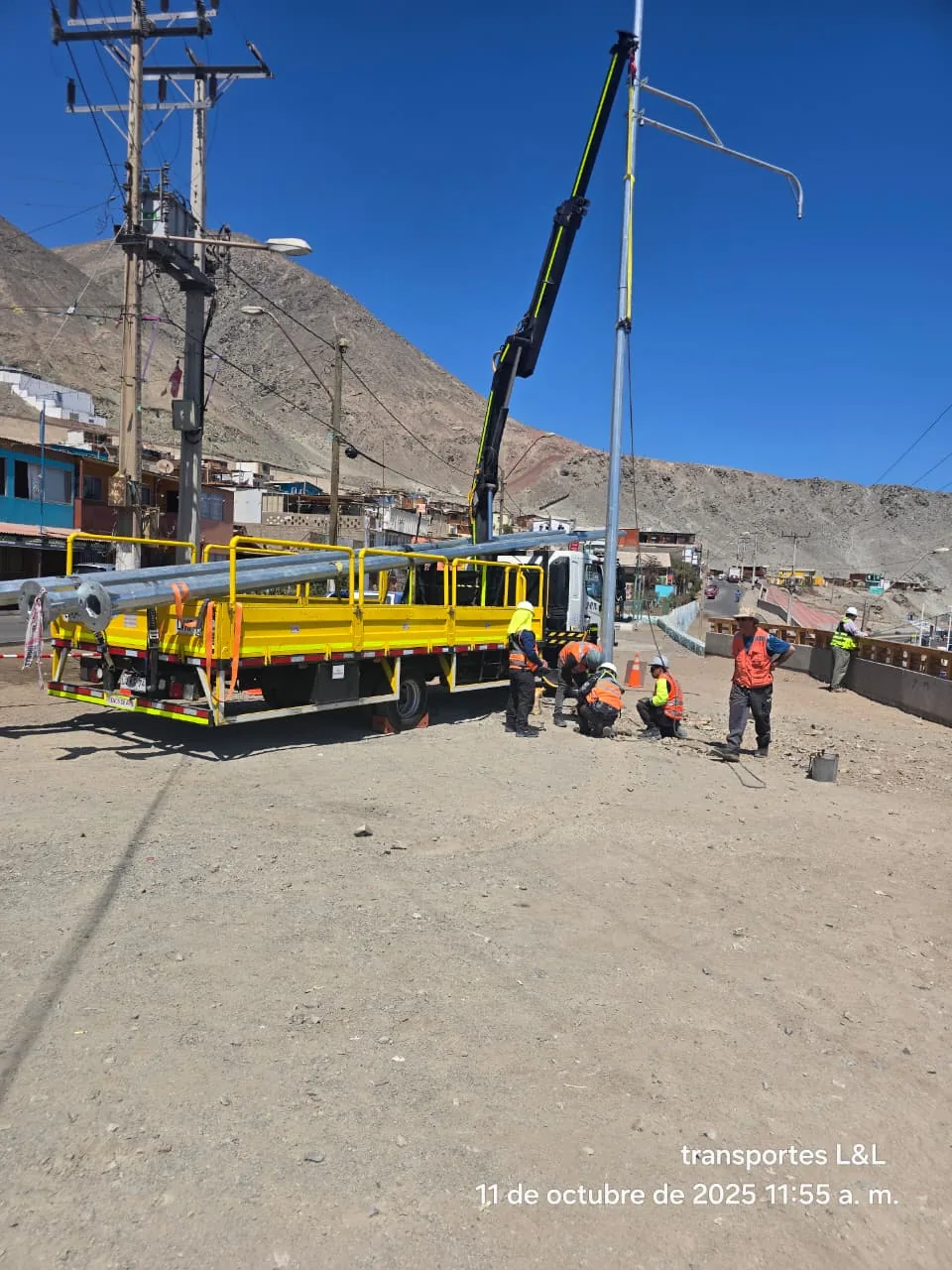 Camión pluma realizando izaje e instalación de postes